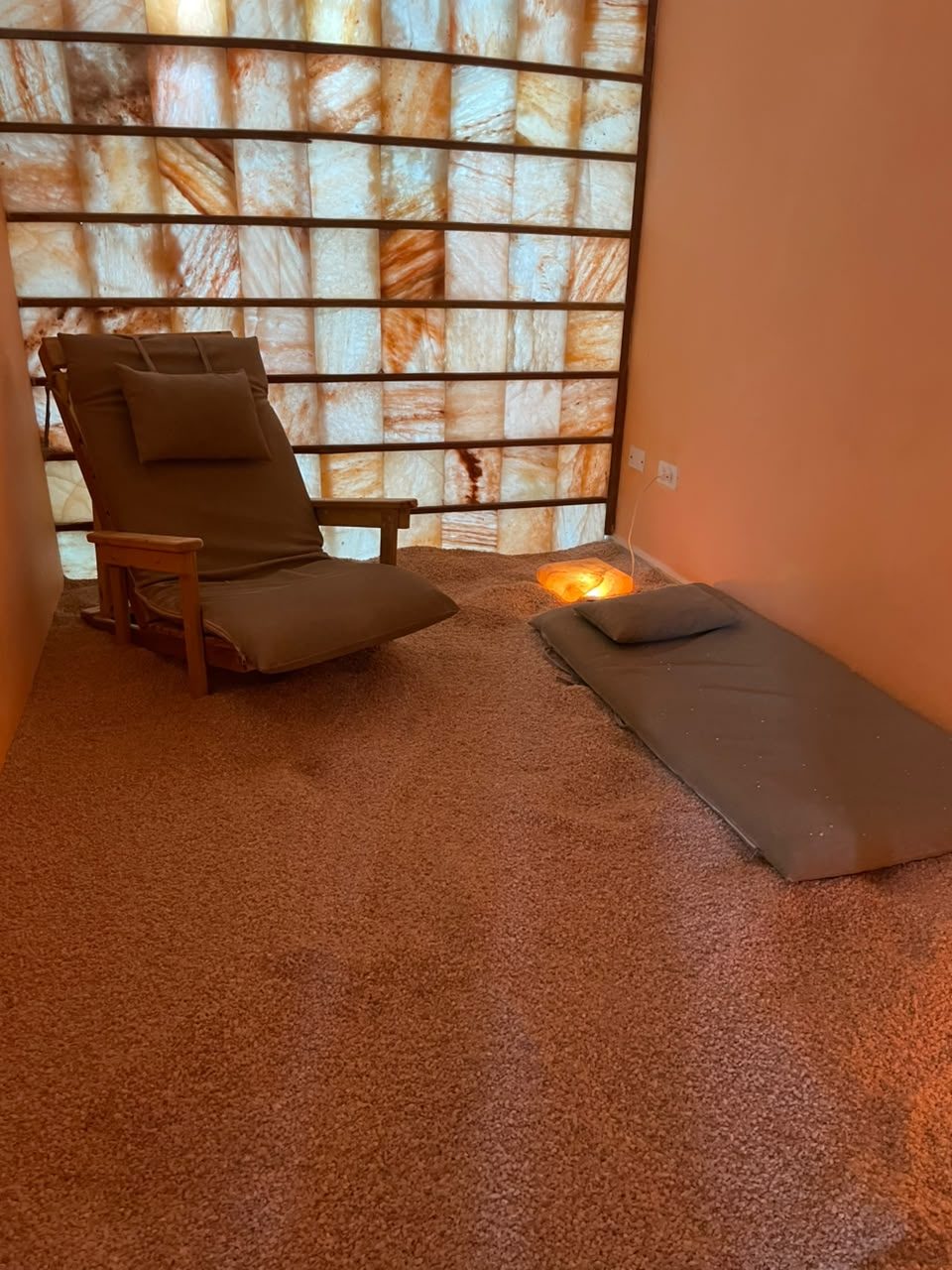 Paneles de bloques de sal retroiluminados, sillón y colchoneta en el cuarto de sal